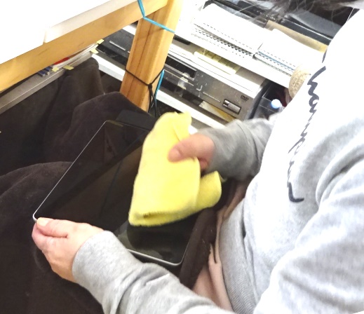 パソコンを左手で押さえ，右手でその画面をクリーニング