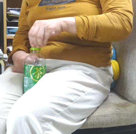 両脚でPETボトルを挟み込んで左手でキャップを閉める