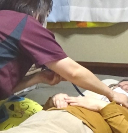 妻の呼吸音をチェックする理学療法さん