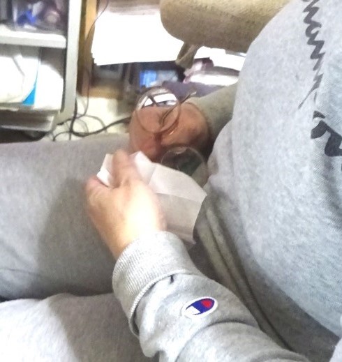 右手で掴んだメガネのレンズを左手で拭く